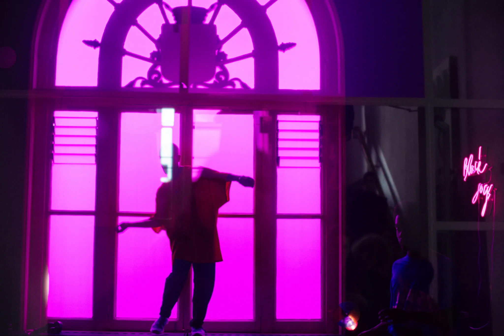 Een performer dansend op een vensterbank, gefotografeerd door een paarse glas