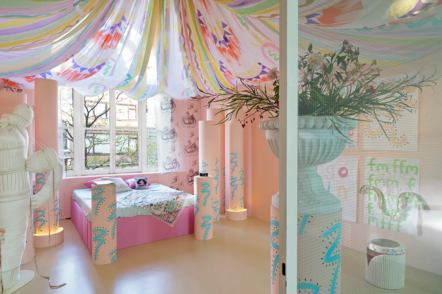 Een flamboyante roze kamer met een bed, beschilderde zuilen, bloemen en gordijnen aan het plafond.