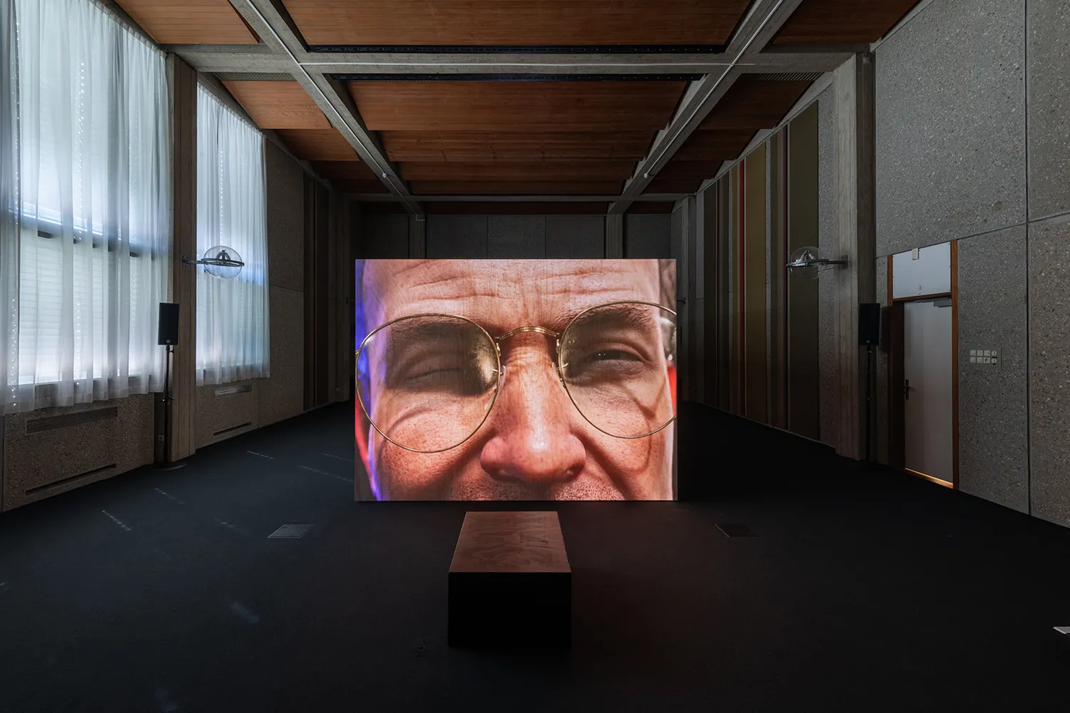 Projectie van een close-up digitaal personage op een houten kist in een voormalige rechtszaal