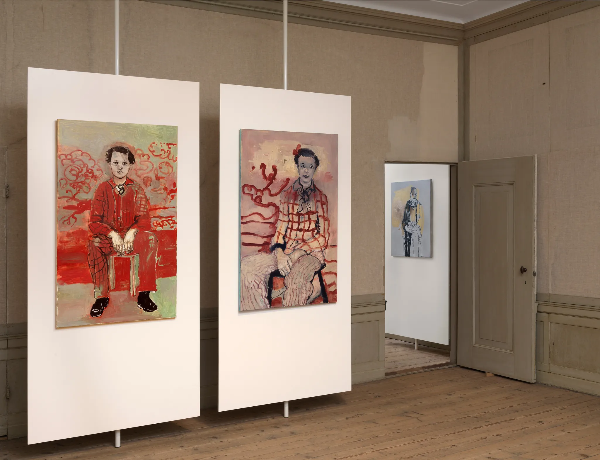 2 schilderijen met de portretten van een persoon zittend in rode tinten en, achter een deur, een derde schilderij van een persoon zittend in grijze tinten