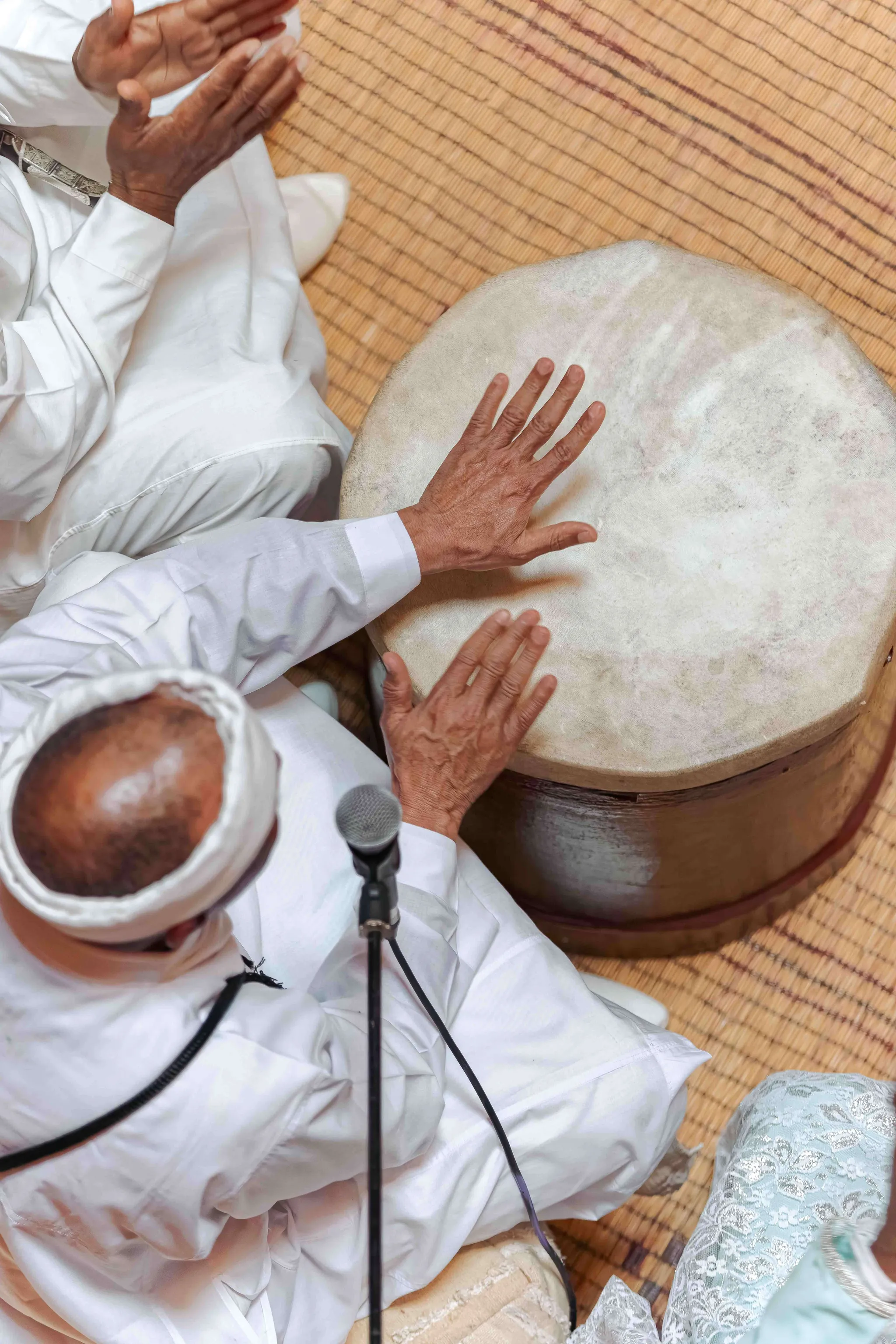 Muzikanten gekleed in witte jellabah klappen in hun handen en bespelen de drums.